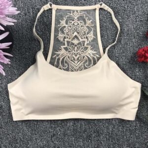 A beige Butterfly Bra with a delicate lace back design laid on a textured grey surface, surrounded by flowers.