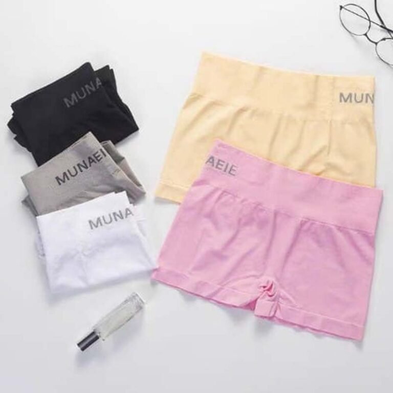 A flat lay arrangement of various colored shorts, including black, gray, white, yellow, and pink, positioned next to a small perfume bottle and a pair of glasses.