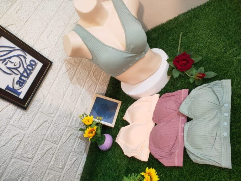 A display of three colorful bras on a mannequin, with a floral arrangement and a framed sign in the background.
