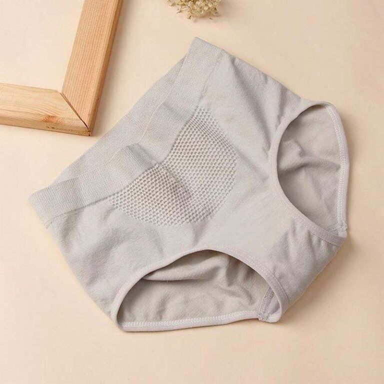 A pair of light gray women's underwear on a beige surface with a wooden frame in the background.