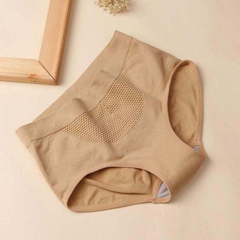 A pair of beige underwear displayed on a light surface with a wooden frame in the background.